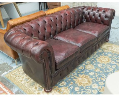 CHESTERFIELD SOFA, three seater, in antique effect red leather, button back, on bun supports, 197cm W. 