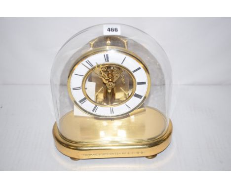 A Junghans Ato brass clock, with enamel ring-shaped roman numeral dial and glass dome.