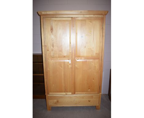 A sycamore two door wardrobe opening to reveal hanging space and single shelf above a single long drawer, 119cms wide.