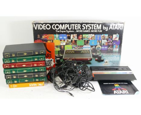 A boxed Atari 2600 games console unit, together with various games cassettes and control units 