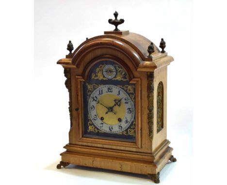 Early 20th century cast brass mounted walnut mantel clock, the arched case with overhanging cornice surmounted by four flamin