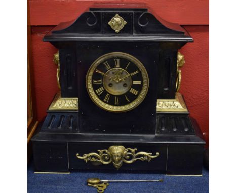 Late 19th century cast brass mounted black marble mantel clock, the plinth shaped case with scrolling pediment over mask and 