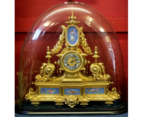 19th century gilt brass clock in Louis XV style, under a large glass dome, the gilt face with blue enamel dial with Roman num