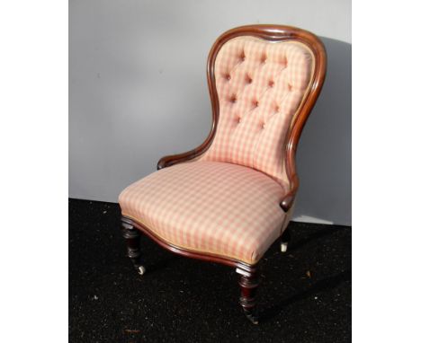 A Victorian mahogany-framed spoon back nursing chair with button-back fabric upholstery on turned legs and castors 