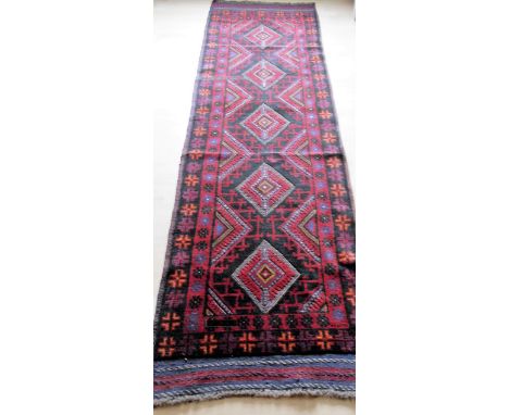 An Afghan hand-knotted Mashwani  burgundy-ground wool runner with central diamond designs, single border and short fringe, 68