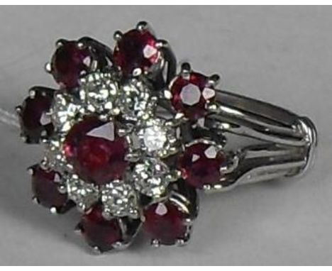 A target-style diamond and ruby cluster ring. Set with nine mixed-cut rubies, one measuring 5.4mm diameter, eight measuring 3