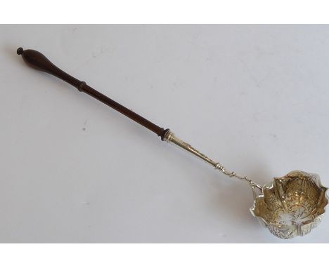 A mid-18th century silver and fruitwood toddy ladle; the lobed bowl embossed with floral, fruiting, scale and waterfall motif