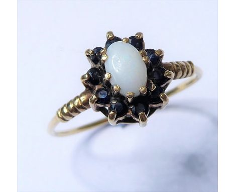 A cabochon opal and sapphire-set cluster ring to the 9 carat yellow gold ornate shoulders and wirework band, hallmarks rubbed