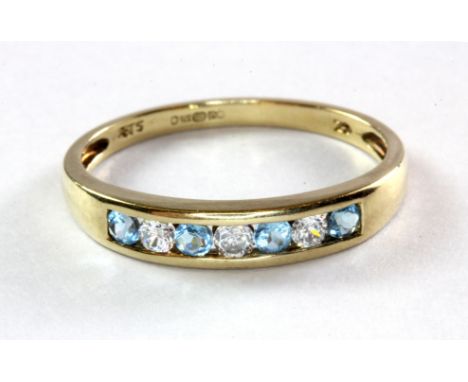 A 9ct (stamped 375) yellow gold blue topaz and white stone set half eternity ring, (P.5).