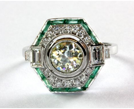 An Art Deco style 18ct (stamped 18k) white gold ring set with a central diamond approx. .88ct surrounded by diamonds and emer