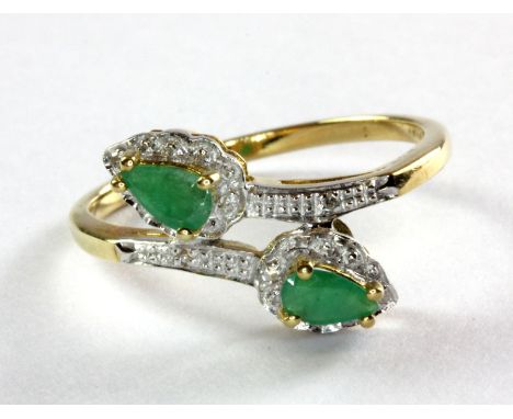 A 9ct (stamped 375) emerald and diamond set crossover ring, (P).