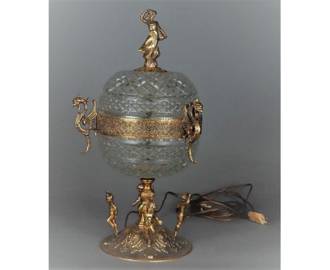 A pressed glass table lamp in the shape of a coupé with a brass frame in the shape of putti and griffins. 20th century.H.: 51