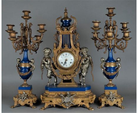 A Garniture de Chéminée consisting of a mantel clock with enamel dial. The bell statues consisting of two satyrs holding up a