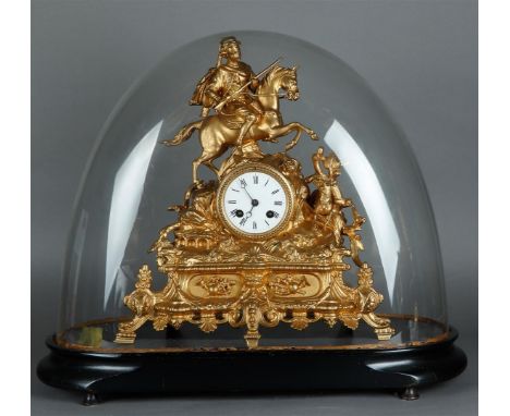 A gold-painted zamac mantel clock decorated with a knight on horseback, in a glass dome. France, 19th century.Afm. (stolp): 3