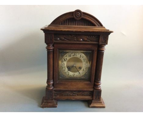 A mahogany cased table clock with fluted column sides.