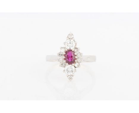 A hallmarked 18ct white gold ruby and diamond cluster ring, set with a central oval cut ruby, measuring approx. 5x4mm, surrou