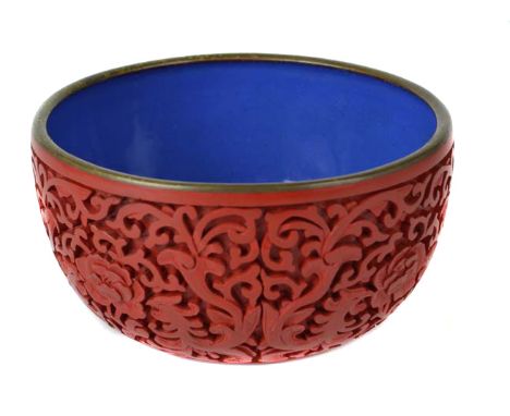 A Chinese cinnebar lacquer bowl with blue enamel interior, decorated with peonies and scrolled fabulous beasts, 11cm diam
