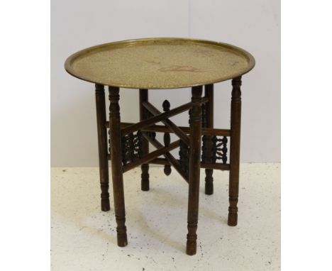 A six legged Middle Eastern folding table, c1920, with engraved brass top with traces of red enamel, 59 x 56cm