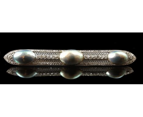 A striking and large Edwardian diamond, blister pearl and platinum brooch, c1910, the three slightly graduated oval shaped gr