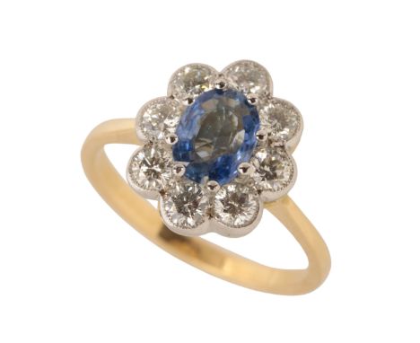 A SAPPHIRE AND DIAMOND CLUSTER RING the oval cut sapphire, within a border of eight brilliant-cut diamonds, on an 18ct yellow