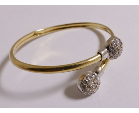 GOLD BANGLE. 14ct gold bangle with stones at each end