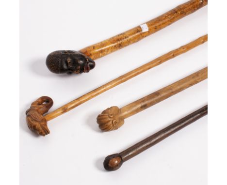 A walking stick, the carved wooden handle modelled as the head of an African man, and three other tribal sticks Condition Rep