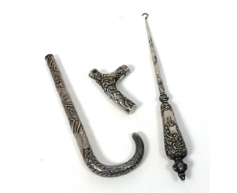 A Japanese Meiji period white metal parasol handle, together with one other smaller and an Edwardian silver handled button ho