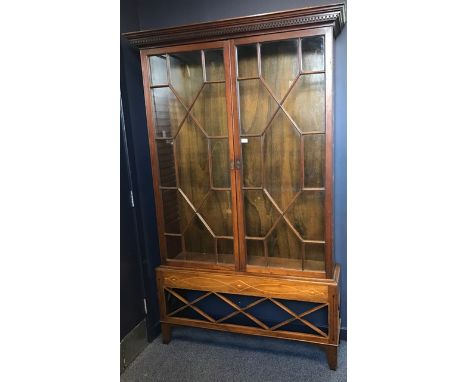 MAHOGANY BOOKCASE ON STAND OF GEORGE III DESIGN the dentil cornice with adjustable shelving below enclosed by two glazed astr