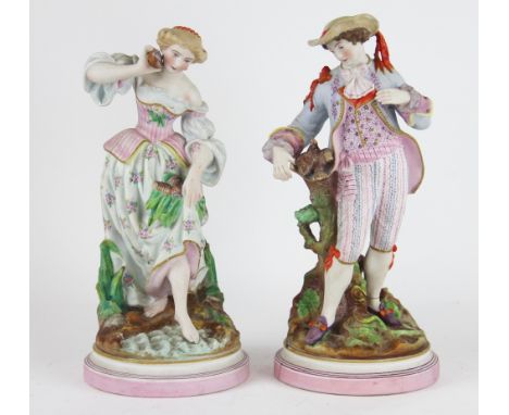 A pair of French bisque figures in 18th century style, each modelled standing and picked out in polychrome enamels, raised on