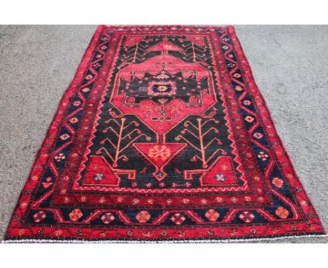 A Persian Lori wool carpet, worked with geometric flowers and motifs against a red and blue ground, 290cm x 152cm