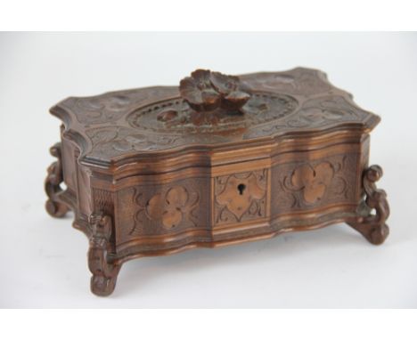 A 20th century Black Forest carved softwood trinket box, with flower knop on scroll feet, 22cm long