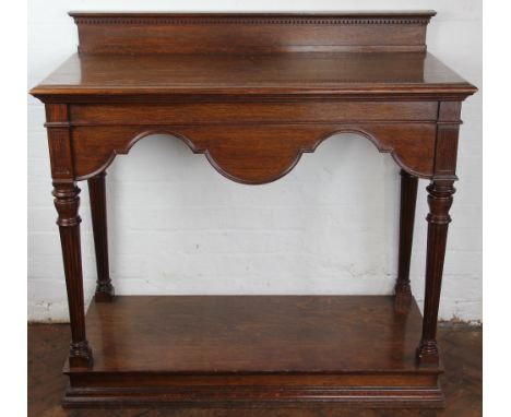 A late Victorian oak two tier buffet by Collinson and Lock, with shaped apron, on turned and fluted tapered legs, on plinth b