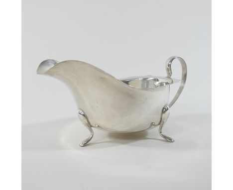 An early 20th century silver sauce boat, of helmet shape, with a plain handle, on three hoof feet, Sheffield 1932, 188g, 20cm