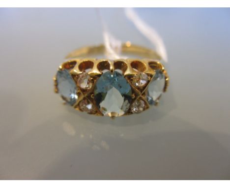 Three stone aquamarine and four stone diamond set ring in a carved half hoop setting