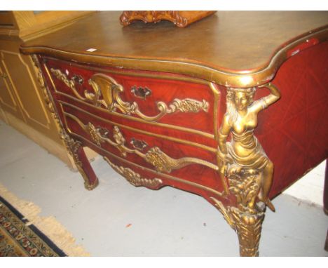 Continental reproduction gilt and red painted two drawer commode with applied carved decoration, the drawers flanked by carya
