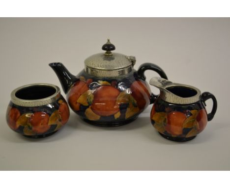 Early 20th Century Moorcroft Pomegranate pattern three piece tea service with beaten pewter mounts, painted and impressed mar