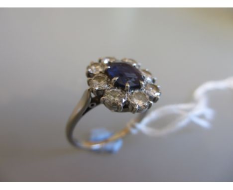 Single stone sapphire and eight stone diamond set oval cluster ring on a white metal mount, estimated total diamond weight 0.