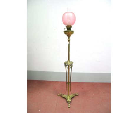 An Early XX Century Floor Standing Brass Oil Lamp, the central column with foliate swags and raised on tripod base with hoof 