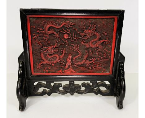 A Chinese table screen with embonised frame and cinnabar coloured centre with dragon decoration, length 22cm