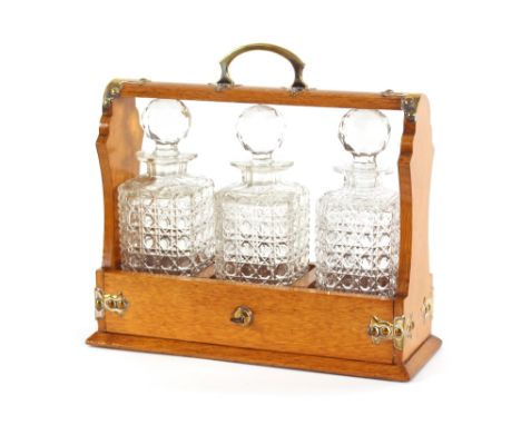 A light oak Tantalus, having plated mounts and fitted three square cut bottles, 34cm wide