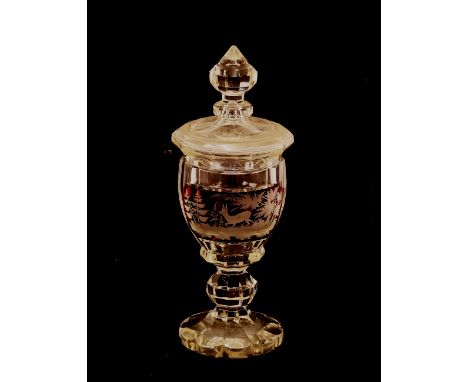 A Bohemian covered glass goblet,&nbsp;the lid surmounted by a faceted finial above a ruby flash panel, depicting stag in a fo