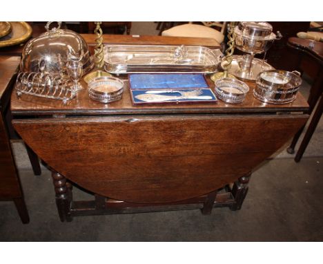 An 18th Century oak gate leg dining table, fitted with a single end drawer beneath rounded drop leaves, raised on turned supp
