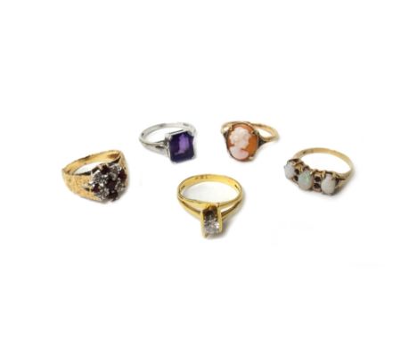 An 18ct gold ring, claw set with a circular cut diamond, in an abstract design, a 9ct gold, ruby and diamond cluster ring, a 