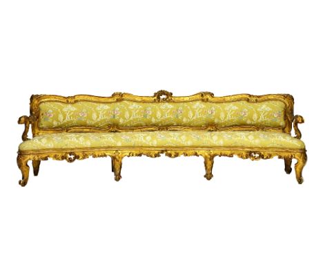 A 19th century curved gilt framed sofa, with opposing 'C' scroll crest and carved floral chased frame, on scroll supports, 26