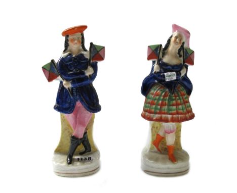 A pair of Staffordshire portrait figures, 19th century, depicting a Highland couple, polychrome decorated, each holding colou