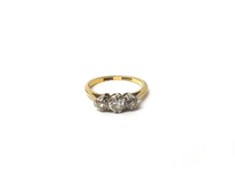 A gold and platinum, diamond set three stone ring, claw set with a row of circular cut diamonds and with the principal diamon