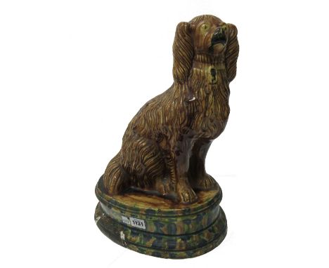 A large pottery model of a spaniel, 19th century, possibly Staffordshire, brown glazed atop a mottle glazed stepped oval base