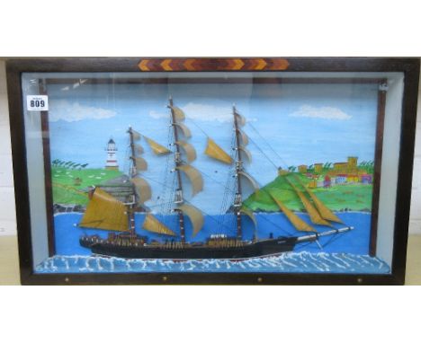 A half block wooden model ship, 'Nicol Burn', fully rigged and mounted against a painted coastal backdrop, housed in a glazed