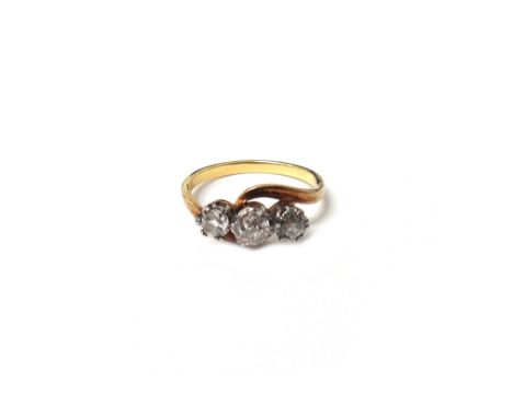 A gold and diamond three stone ring, claw set with a row of cushion shaped diamonds and with the principal diamond mounted at