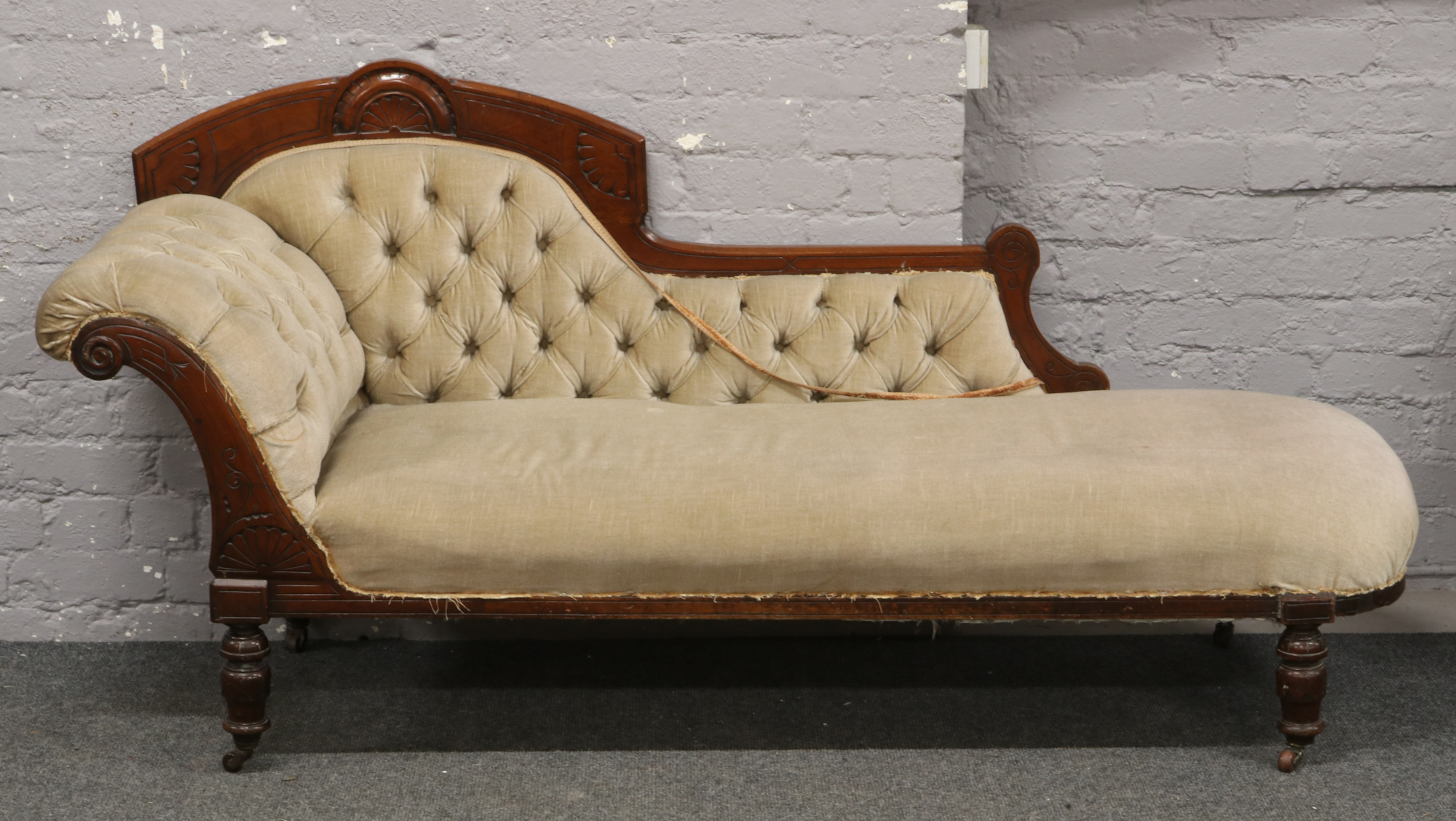 A Victorian chaise lounge with deep buttoned upholstery.